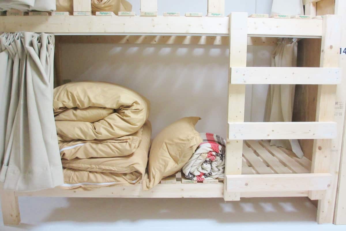 Uma cama beliche com escada, cortina e travesseiro.