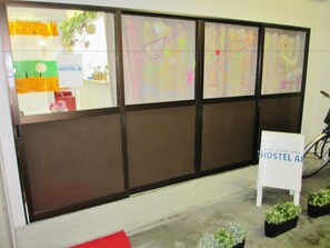 A hostel interior with a large window displaying colorful artwork, a signboard, and potted plants. - Hostel AI (Osaka)