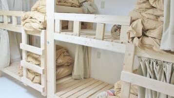 Bunk beds with storage compartments, each containing rolled-up blankets and pillows.
