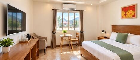 Una habitación de hotel con cama, escritorio con silla, televisor y ventana con cortinas.