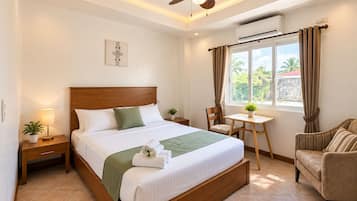Habitación de hotel con cama, escritorio, silla, ventilador de techo y aire acondicionado.