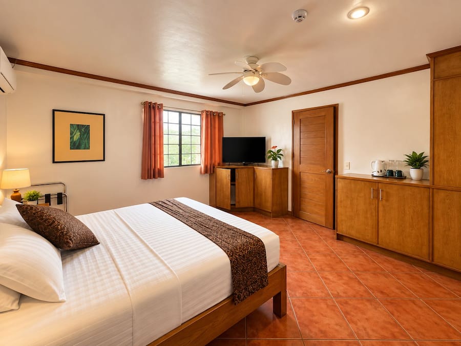 Een hotelkamer met een bed, bureau, televisie en kledingkast.