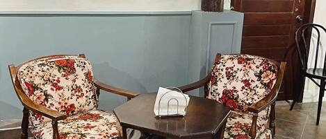 A pub hotel interior with two floral armchairs, a small wooden table, and a wooden door with "PUB HOTEL" sign.
