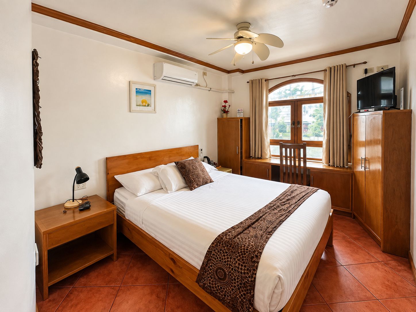 A hotel room with a bed, a desk, a wardrobe, a television, and a window with curtains.