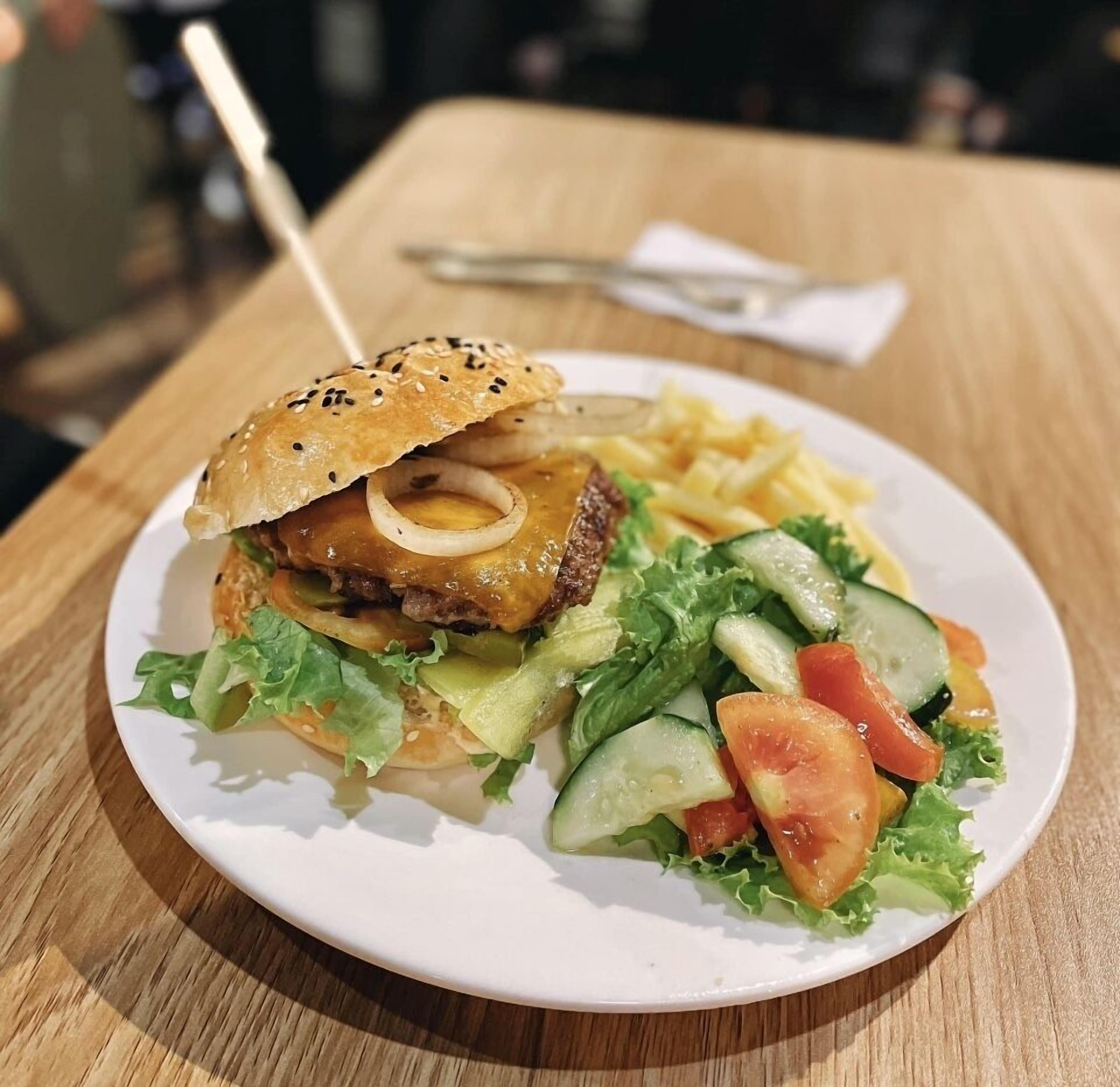 A plate with a sandwich, salad, and fries on a wooden table.
