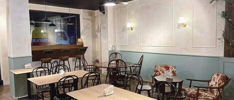 L’intérieur d’un restaurant, avec de nombreuses tables et chaises, un bar et des éléments décoratifs sur les murs.