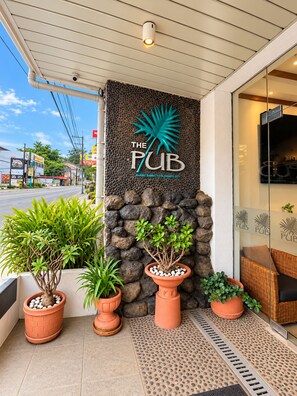 A building entrance with a sign for 'The Pub' and a stone wall with potted plants. - The Pub Hotel (Olongapo)