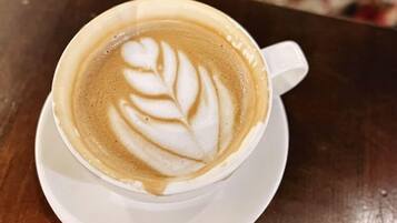 Une tasse de café surmontée d’un motif en latte art, posée sur une soucoupe blanche.