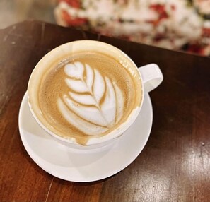 A cup of coffee with latte art on a white saucer. - The Pub Hotel (Olongapo)