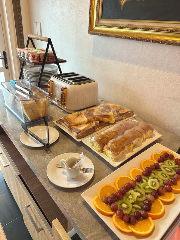 Un bufé de desayuno con diversas opciones de comida, como pan, pasteles y fruta.