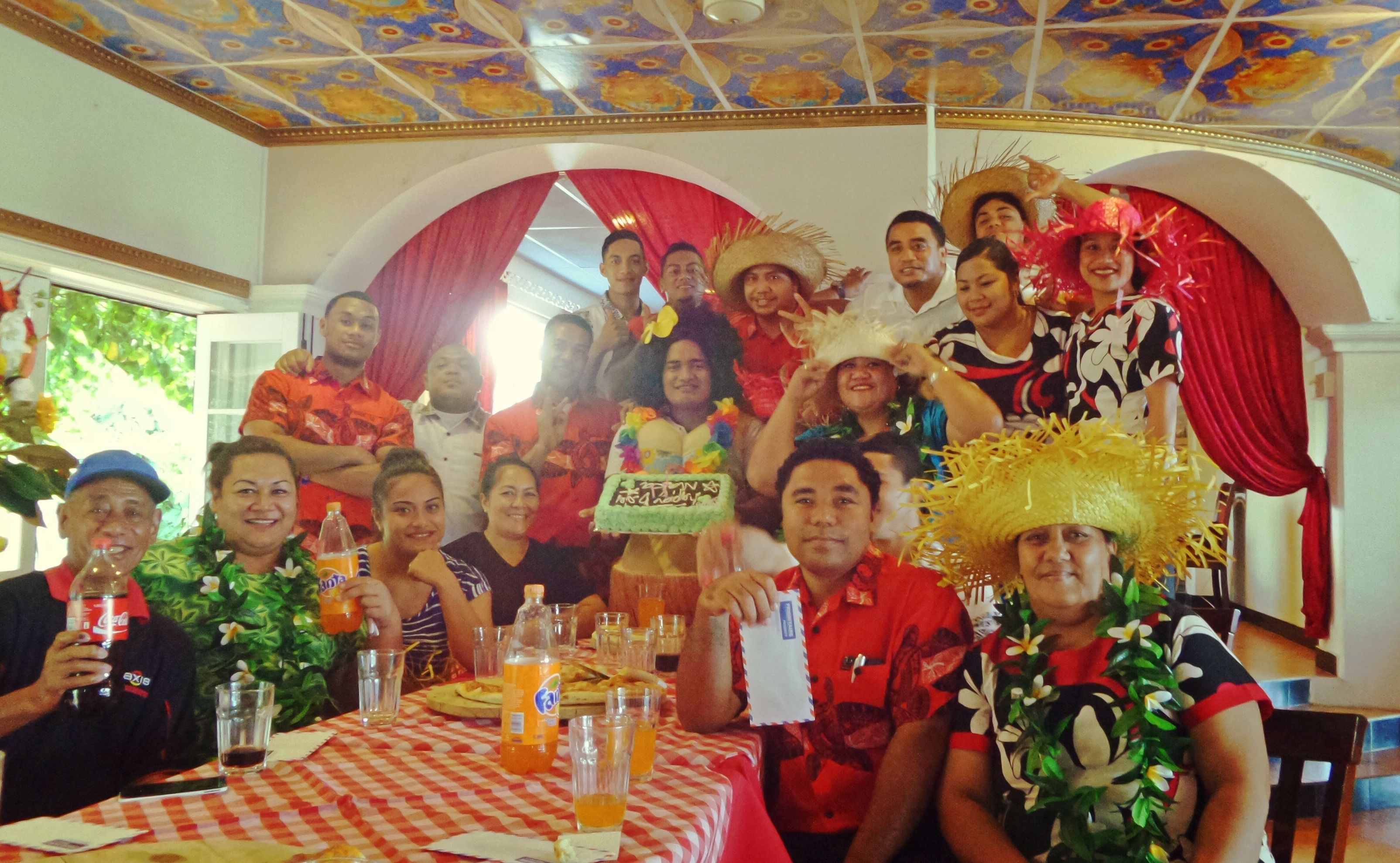 A group of people at a dining table with a checkered tablecloth, bottles of soda, and glasses.