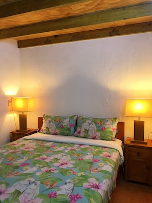 A bedroom with a floral bedspread, two bedside lamps, and a wooden headboard. - The Tropical Villa (Puke)