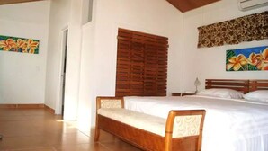 Une chambre avec un lit en bois, une fenêtre avec des volets en bois et un tableau de fleurs accroché au mur.