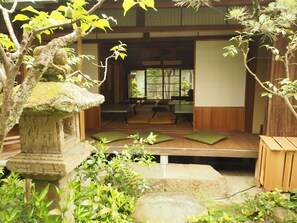 A traditional Japanese-style room with tatami flooring, a low wooden table, and cushions. - Naramachi Hostel & Restaurant (Nara)