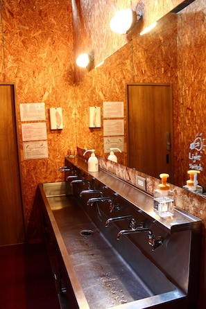 A public restroom with a long bench, multiple sinks, and a mirror. - Naramachi Hostel & Restaurant (Nara)