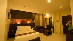 Een hotelkamer met een groot bed, een bank, een bijzettafeltje en een televisie.
