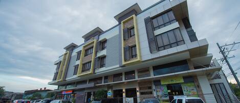 A multi-story building with a modern architectural design, featuring a ground floor with commercial spaces and upper floors with residential units.