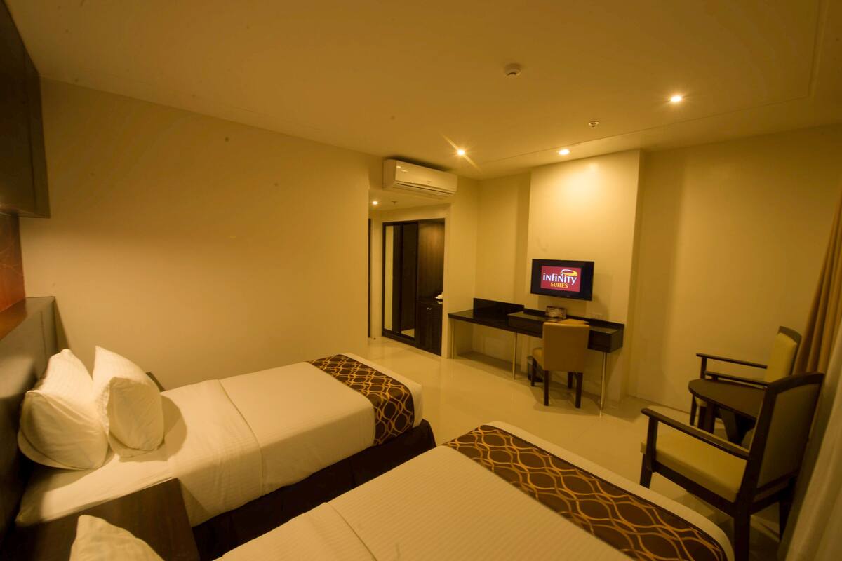 Una habitación de hotel con dos camas, un escritorio, una silla y un televisor.