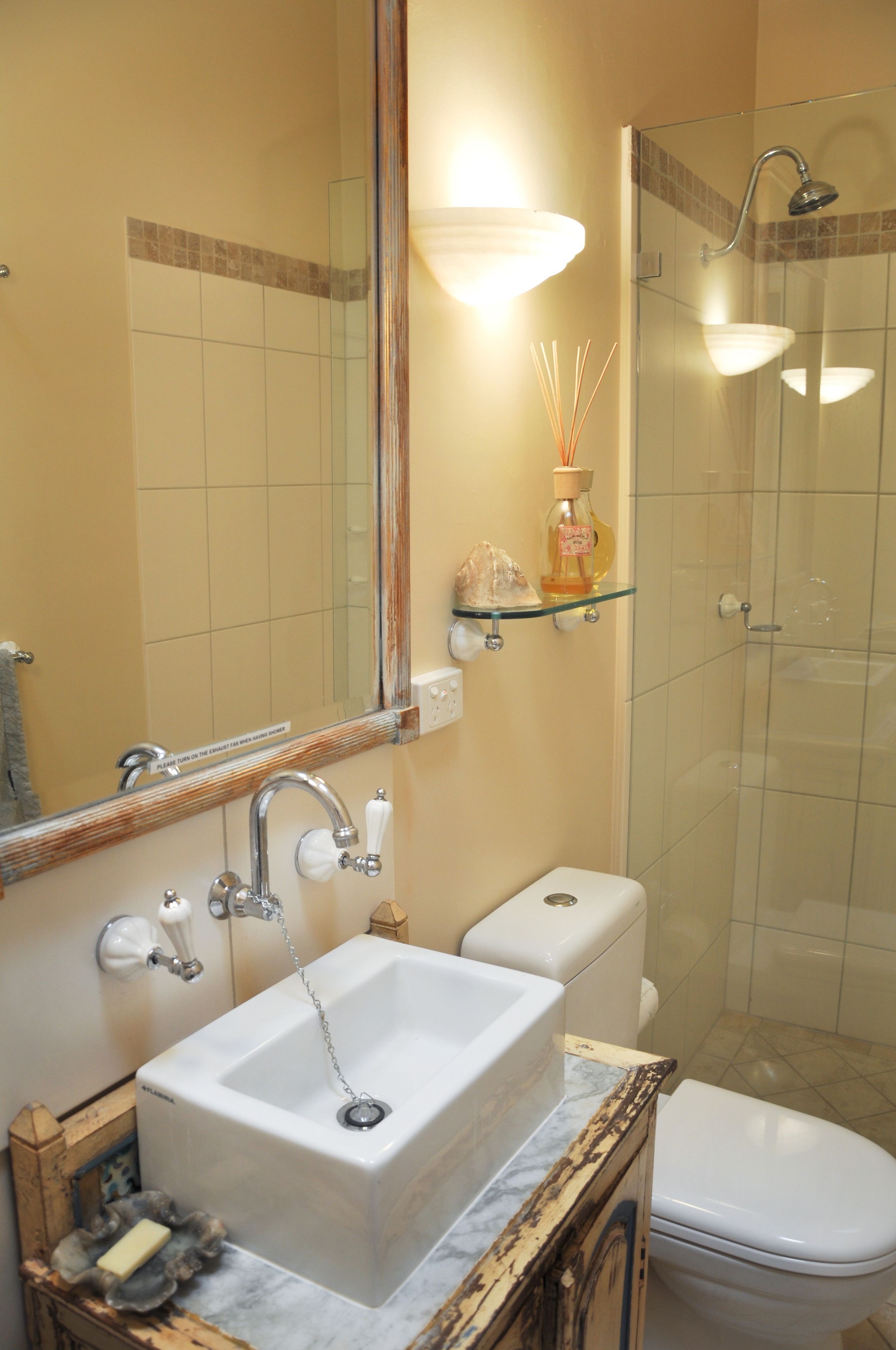 A bathroom with a large mirror, a sink, a toilet, and a glass-enclosed shower.