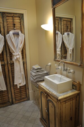 A bathroom with a rustic wooden door, a white sink, and a mirror above it. - Athelney Cottage (Hackney)