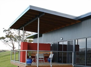 A modern building with a covered outdoor area, large windows, and a view of the surrounding landscape. - Black Rock Retreat (Howth)