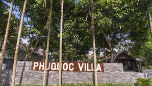 Letrero de Phjuquoc Villa, con un muro de piedra y exuberante follaje.