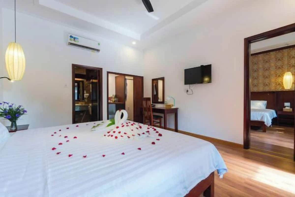 A hotel room with a bed, a desk, a chair, a TV, and a mirror.