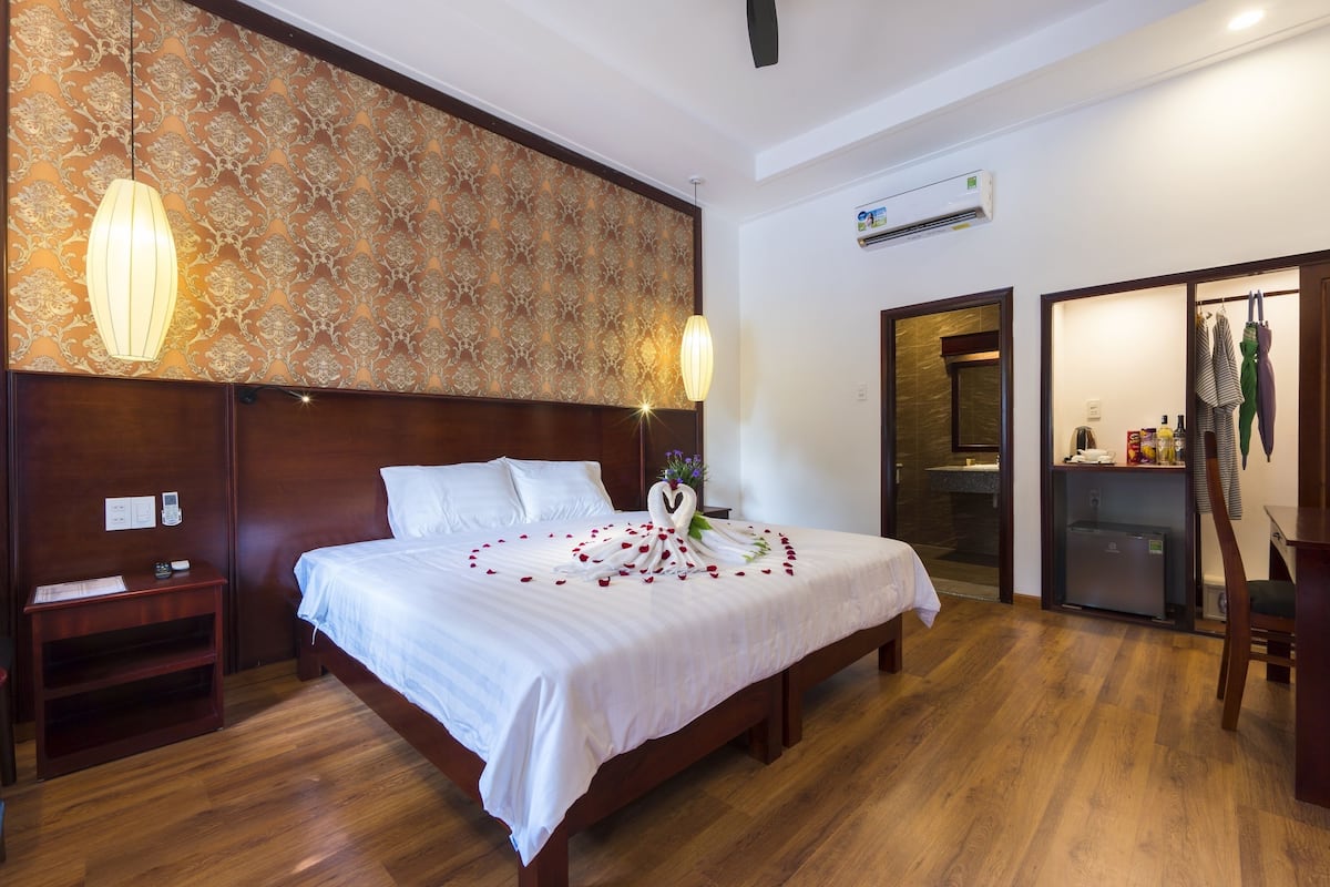 A hotel room with a large bed, wooden headboard, and a decorative wall.
