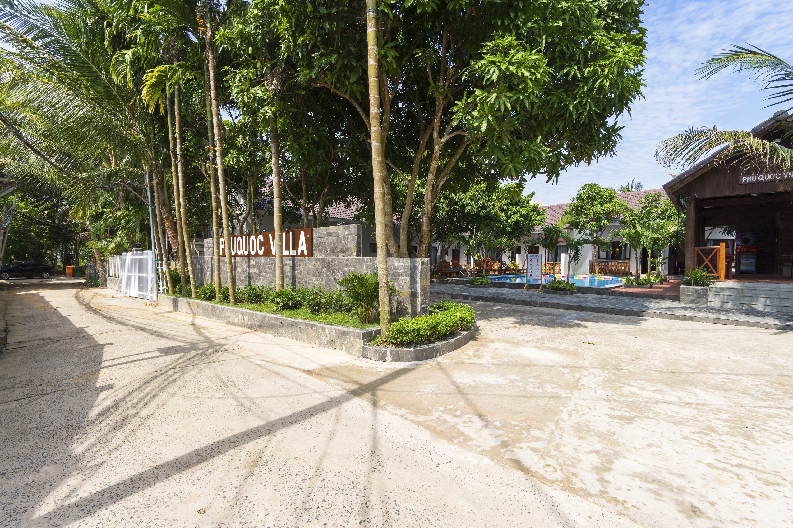 A sign for 'P. UQOC VILLA' with a paved entrance and surrounding greenery.