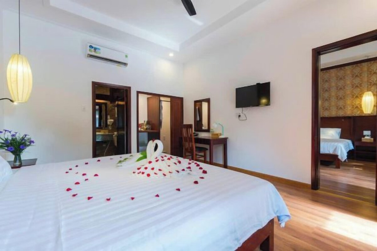 A hotel room with a bed, a desk, a chair, a TV, and a mirror.