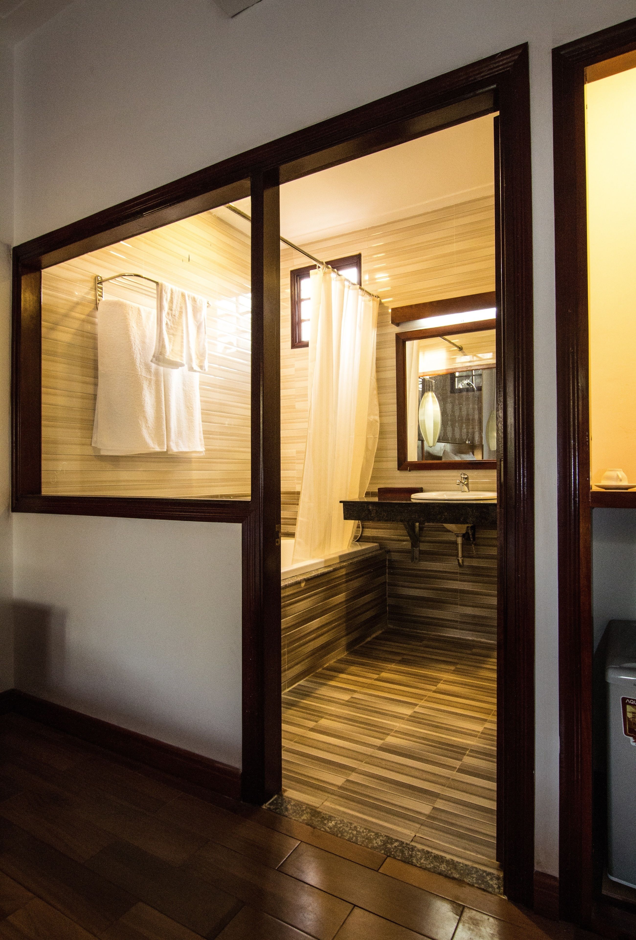 A bathroom with a wooden floor, a sink, a mirror, and a towel rack.