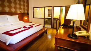 Habitación de hotel con cama, escritorio con lámpara, teléfono y espejo.