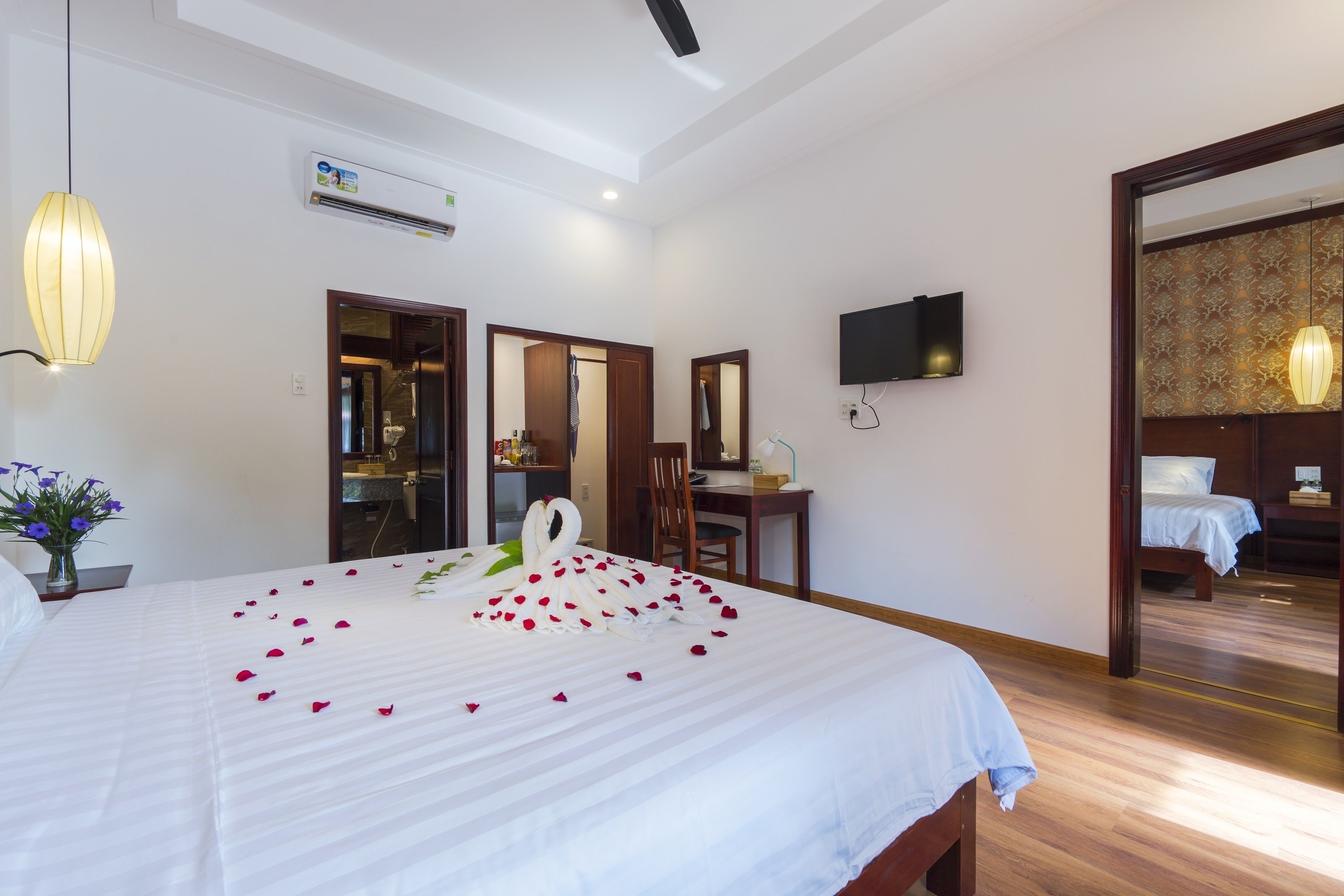 A hotel room with a large bed, a desk, a chair, a television, and a mirror.