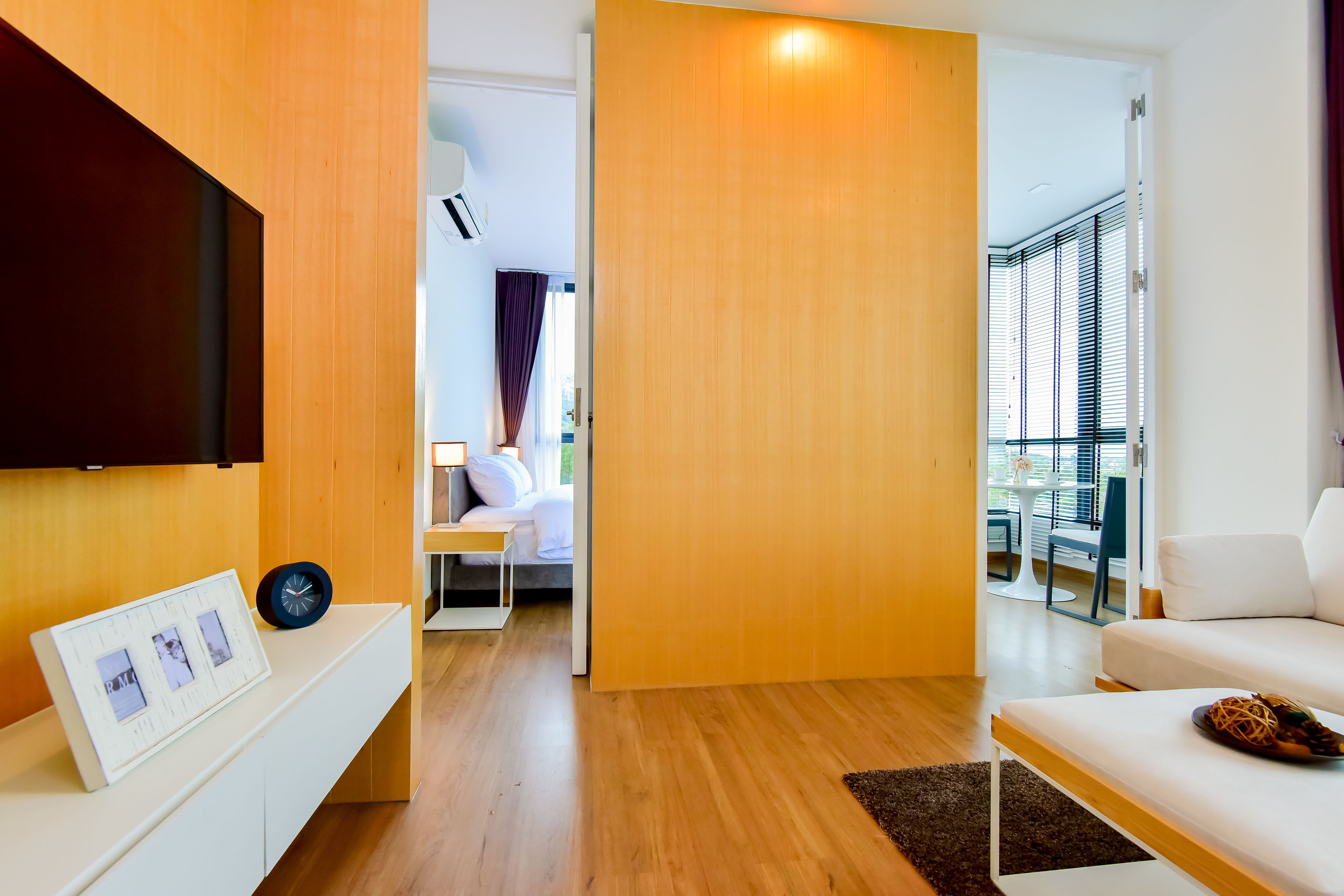 Un salon moderne avec un téléviseur à écran plat, un canapé blanc et un plancher en bois.