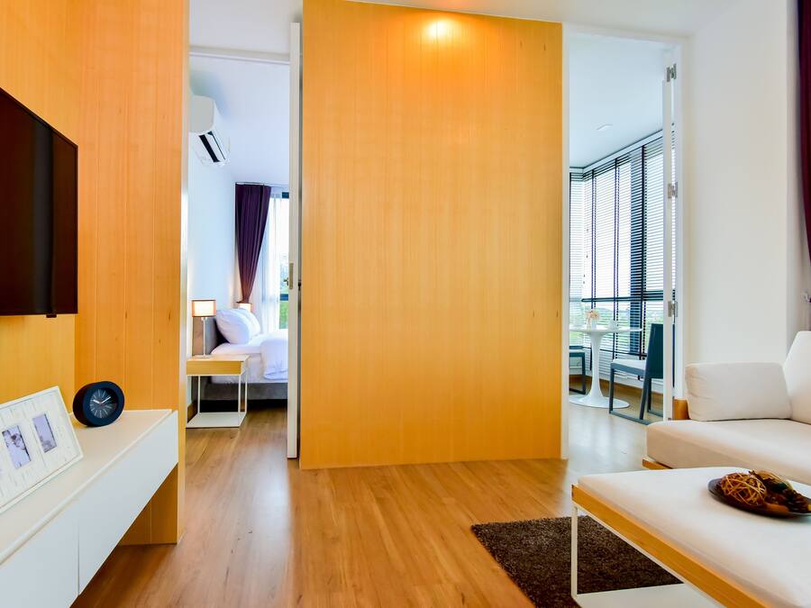 Ein modernes Wohnzimmer mit einem Flachbildfernseher, einem weißen Sofa und Holzboden.