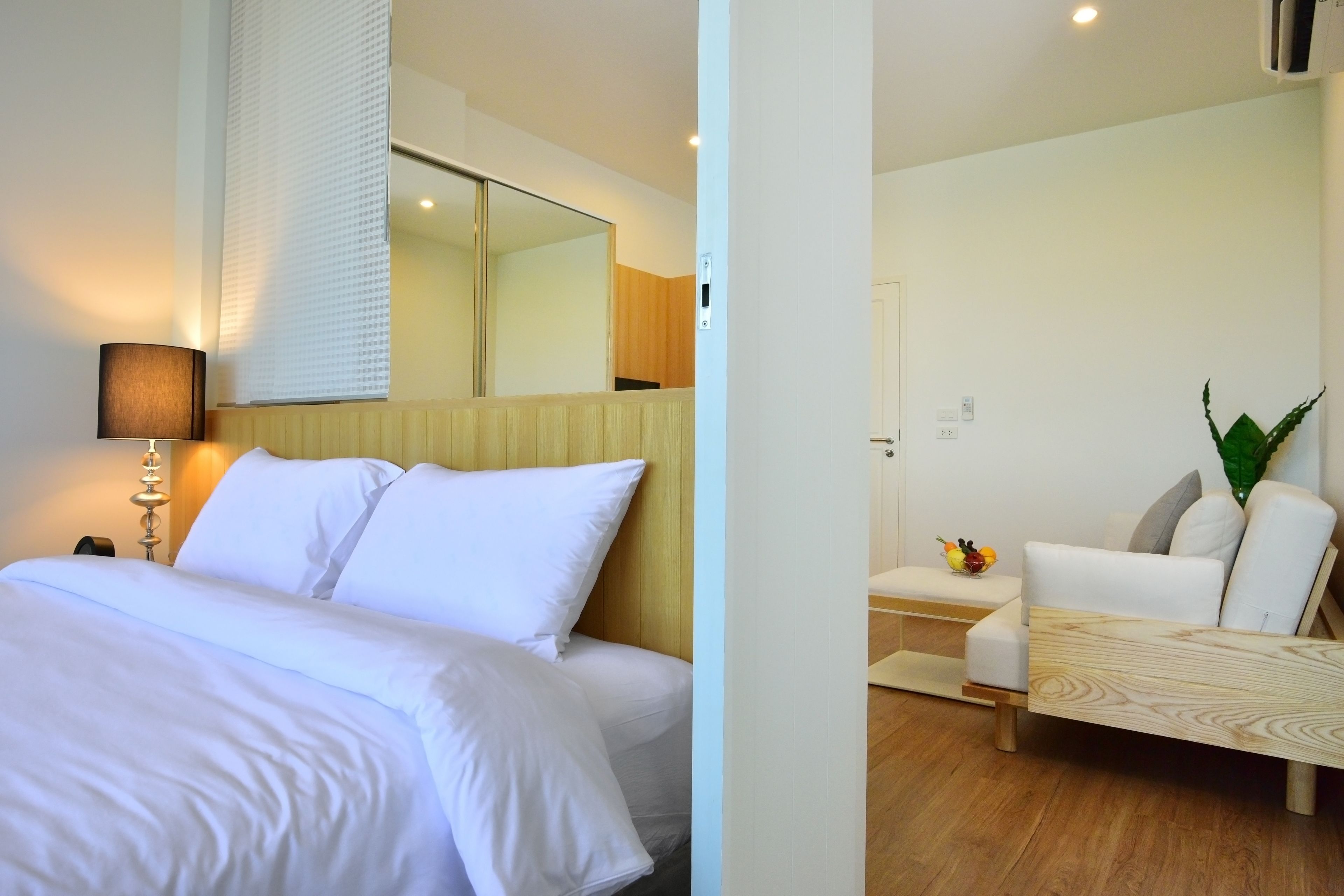 A hotel room with a bed, bedside lamp, and a wooden headboard.