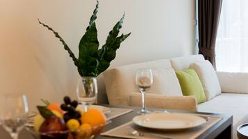 A dining area with a table set for two, a bowl of fruit, and a potted plant.