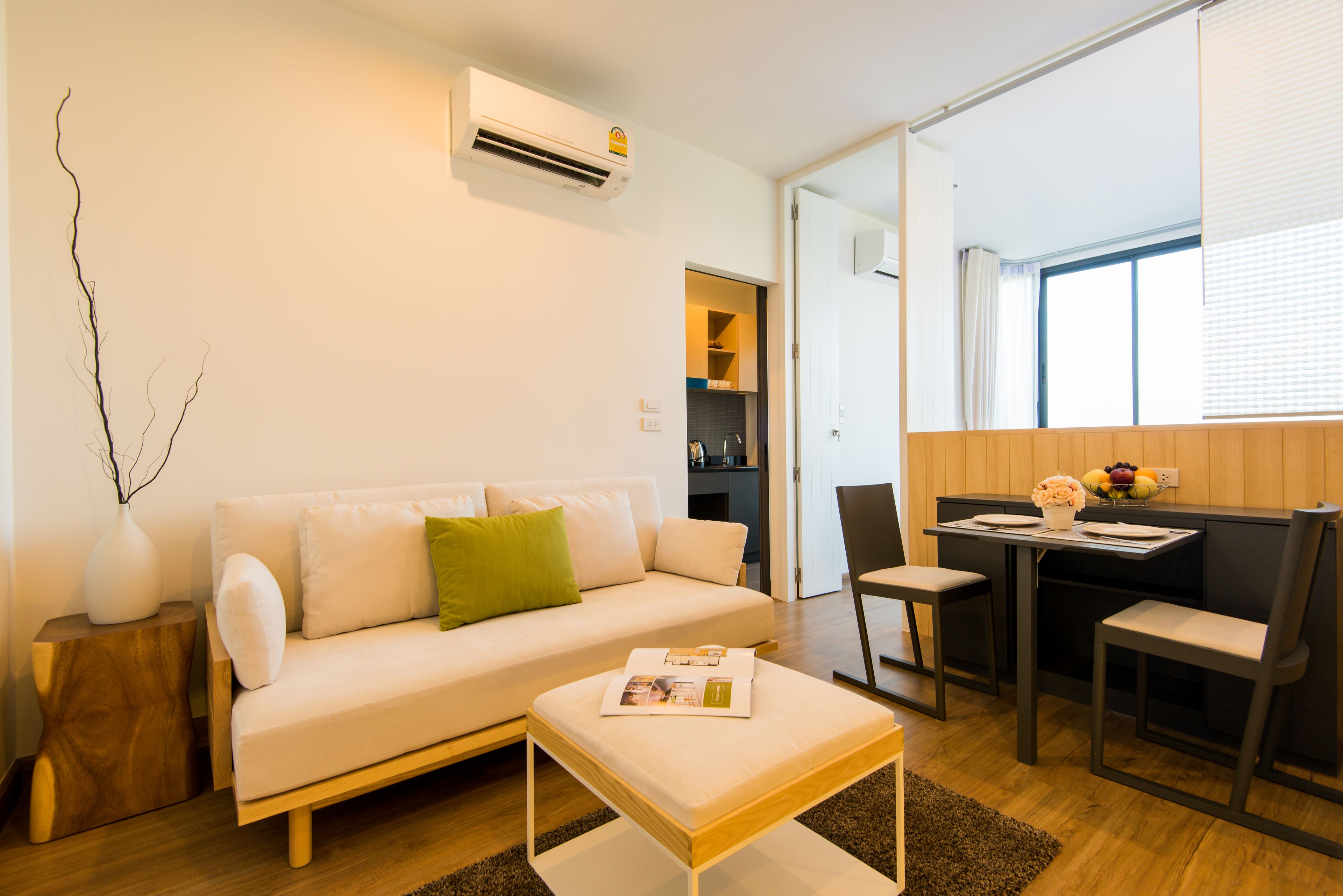 A modern living room with a sofa, a coffee table, and a dining area with a table and chairs.