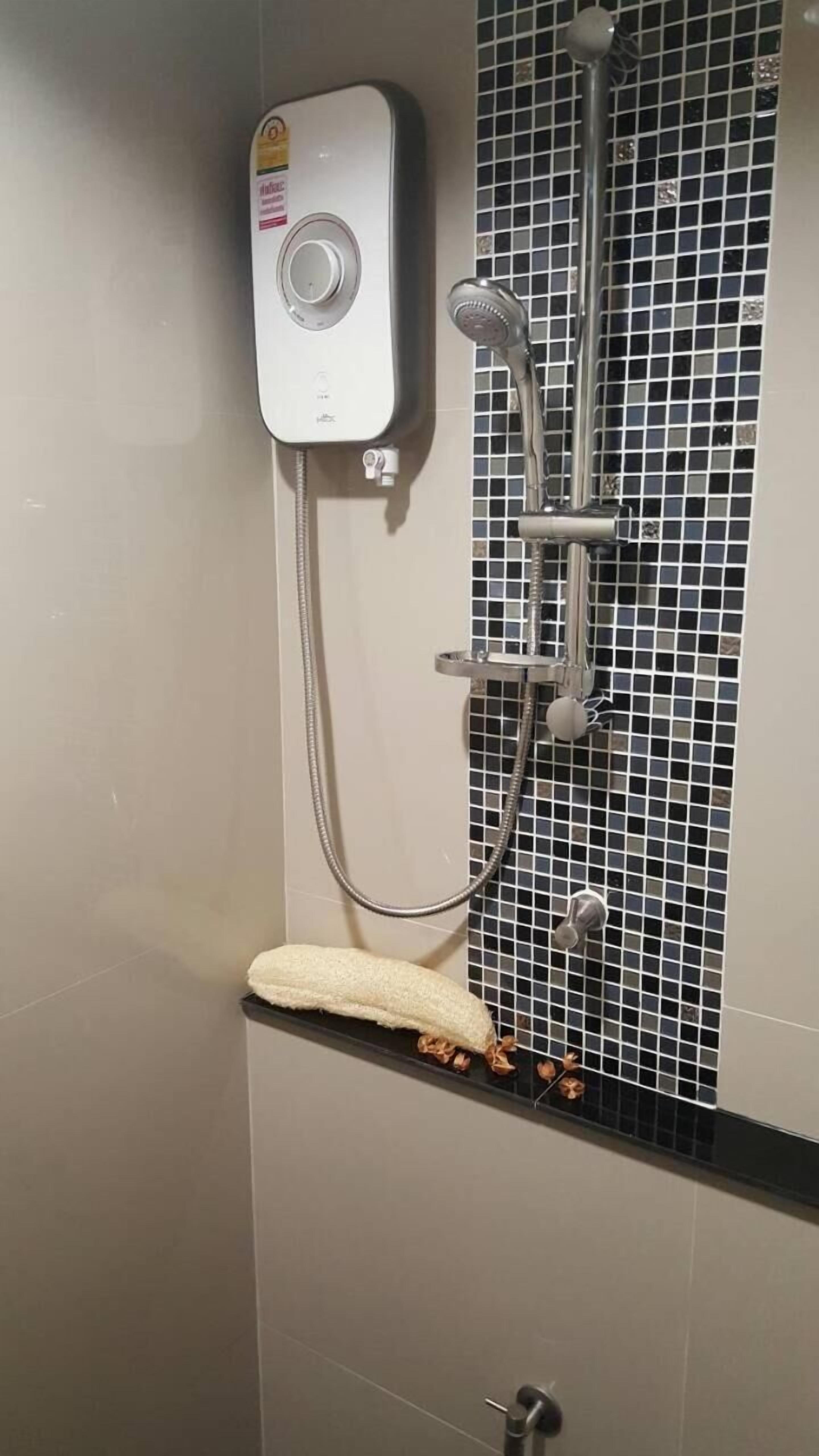 A shower with a handheld showerhead and a wall-mounted control panel.