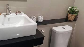 A bathroom with a white sink, a toilet, and a mirror above the sink.