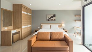 Ein modernes Schlafzimmer mit einem Bett, einem Holzschrank, einer Couch und einem Schreibtisch.