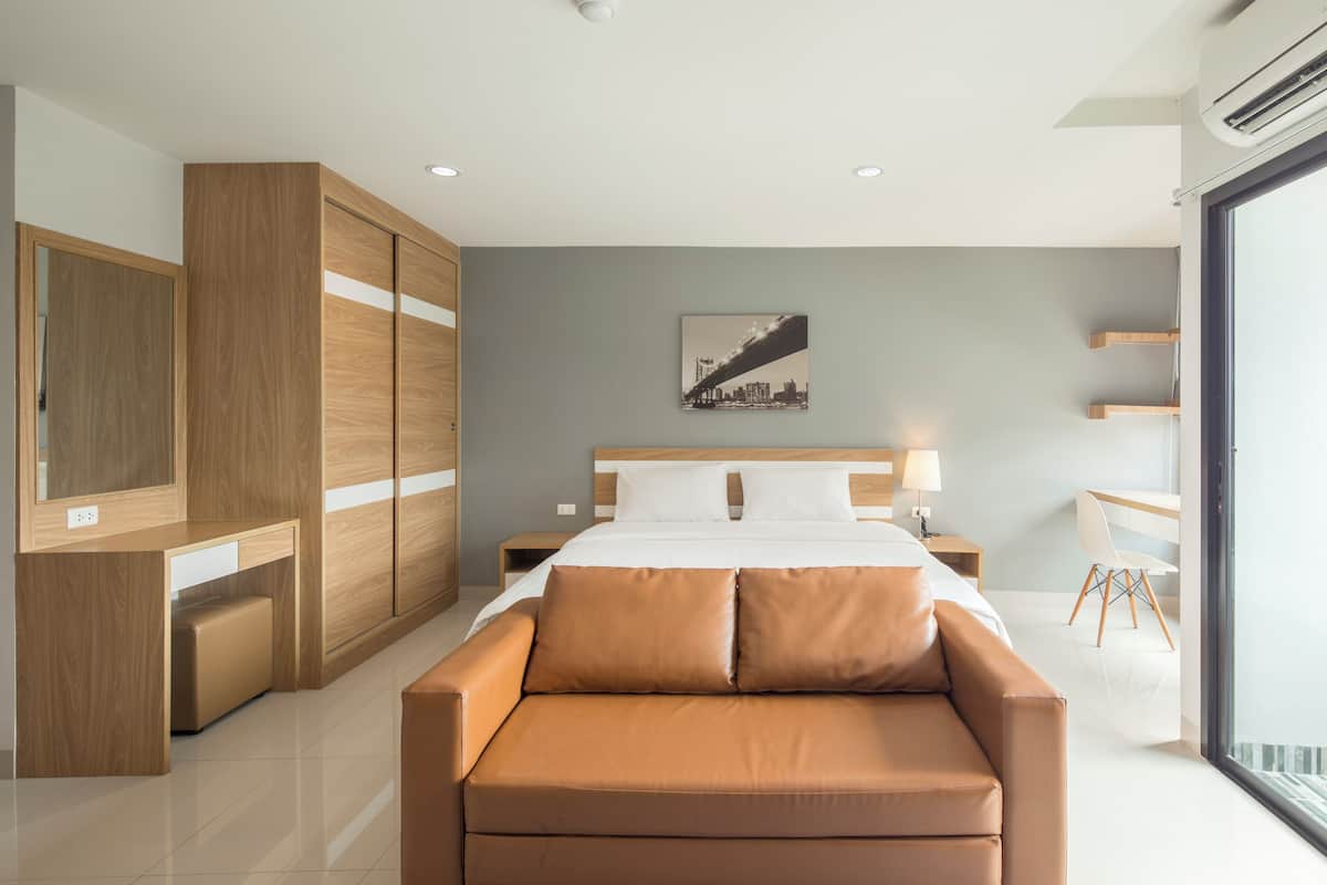 A modern bedroom with a bed, a wooden wardrobe, a sofa, and a desk.