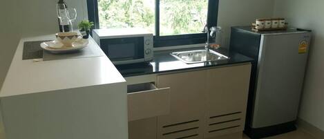 Una cocina compacta equipada con microondas, lavamanos y refrigerador.