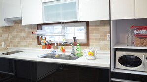 Una cocina moderna con armarios blancos, un lavamanos de acero inoxidable, un microondas y una ventana sobre el lavamanos.
