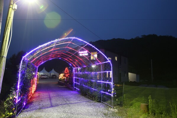 An illuminated archway with a sign that reads "Tropical Cafe." - Pension Cafe Yoon & Park (Yangpyeong)