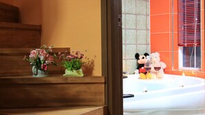 Un baño con bañera, escalones de madera y dos arreglos florales sobre los escalones.