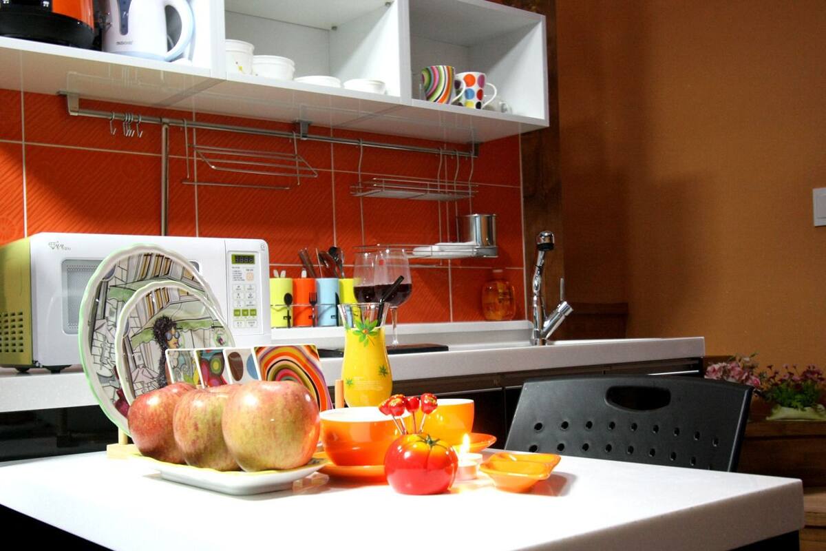 A kitchen with a white countertop, a microwave, and various kitchen utensils.
