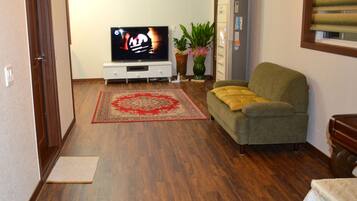 A living room with a television, sofa, and a potted plant.