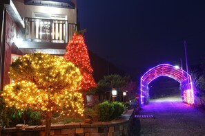 Un sendero lleva a una casa con un árbol de Navidad y un arco decorativo.