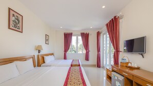A hotel room with two beds, a TV, a desk, and a window with curtains. - T&T Resort And Spa (Phu Quoc)